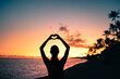 © kieferpix - silhouette of a woman on the beach making heart shape with hands.  Love, and peace in nature concept.