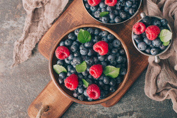 Sweet, fresh blueberry with raspberry in wooden and metal plate on dark background. Organic food.