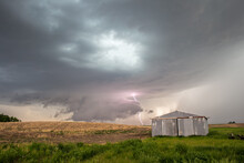 Storm And Wall Cloud With Lightning Bolt Behind An Old Farm Building On The Plains.