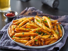 Plate Of Crispy Seasoned French Fries With Parsley Garnish