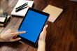 © Rymden - Mockup image of a woman using digital tablet with blank screen on wooden table. Close up photo of female hands holding device vertically