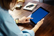 © Rymden - Mockup image of a woman using digital tablet with blank screen on wooden table. Close up photo of female hands holding device vertically