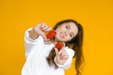 Close-up of a sexy female eating fresh strawberry. Sexual lips, red lipstick. Healthy food concept. Yellow background.