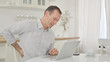 © stockbakers - Middle Aged Man with Laptop having Back Pain at Home