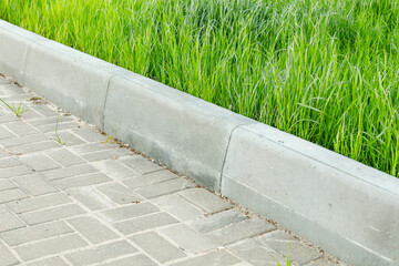 Sticker - A curbstone separates the pedestrian zone from the green tall grass of the lawn. City improvement