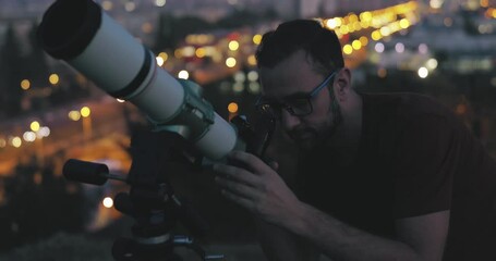 Wall Mural - astronomer with a telescope watching at the stars and moon with blurred city lights in the backgroun