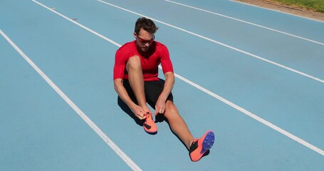 Wall Mural - Athlete sprinter getting ready to run tying shoe laces on stadium running tracks. Man track runner preparing for race marathon training outdoors. Fitness and athletics sports.