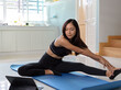 © bongkarn - Woman wearing sportswear and work out at home, practicing yoga, stretching on yoga mat