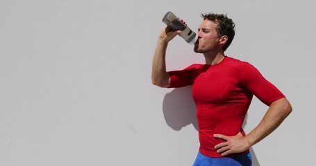 Wall Mural - Fitness man runner drinking water bottle after workout. Running person taking a break after run. Fitness athlete breathing catching breath in summer outdoor training.