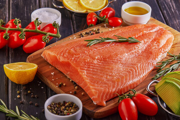 Sticker - Raw salmon fillet pepper salt dill lemon rosemary and cherry tomatoes on a dark wooden table.