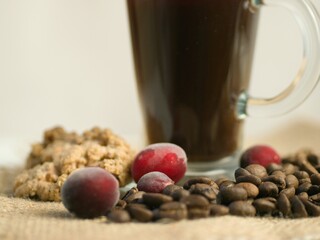 Poster - Soft focus of roasted coffee beans with a blurry glass of coffee in the background