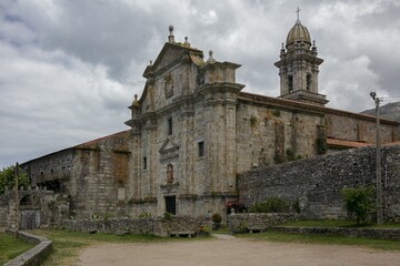 Old Oia Monastery and its stone wall under a cloudy sky in Galicia, Spain