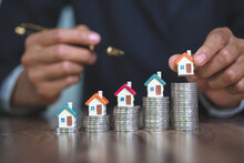 Woman hand hold a  home model put on the stack coin with growing, Savings money for buy house and loan to business investment for real estate concept.