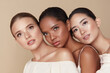 Beauty. Diversity Group Of Models Portrait. Multicultural Women With Nude Makeup And Smooth Perfect Skin Standing Against Beige Background. Gentle Multi-Ethnic Girls Hug Each Other And Looking Away.