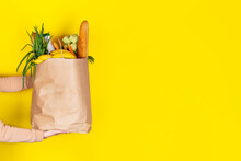 Girl Or Woman Holds A Paper Bag Filled With Groceries Such As Fruits, Vegetables, Milk, Yogurt, Eggs Isolated On Yellow.