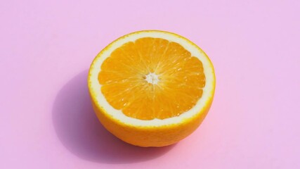 Wall Mural - Rotating orange on a pink background isolate. Juicy fresh yellow orange in the summer sunlight on a colored pastel background. Fresh juices, fruits, vitamin and summer concept.