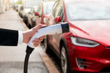 Wall Mural - Hand with charger on a background of electric car 