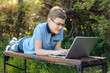 © Наталья Канищева - A teenager with a laptop on a park bench. Distance learning. Learn anywhere.