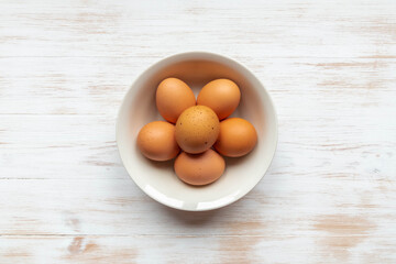 Free-range organic brown eggs in bowl on wood background with copy space