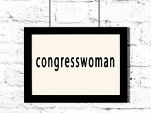 Black Frame Hanging On White Brick Wall With Inscription Congresswoman