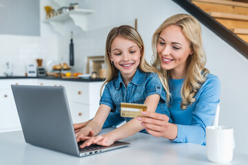 Happy mother and daughter shopping online with laptop and credit card at home