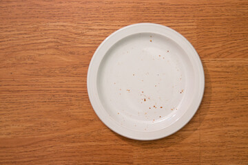 Empty plate with bread crumbs with wooden background.