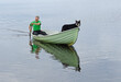 Man with dog on boat on lake. Taivalkoski, Finnish Lapland