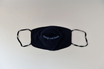 Dark protective mask with phrase stop racism on a gray background