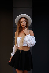 Tanned girl in a white hat and summer makeup on a black background