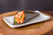 Salmon temaki sushi on white plate in black background