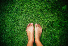 Women's Barefoot With French Manicure On A Green Grass