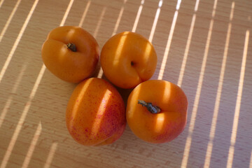 Delicious, fresh and ripe apricots on a wooden table bathed in cosy yellow daylight