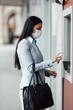 © Dusko - Elegant woman with protective mask standing on city street and using alcohol spray to disinfect her hands after use of ATM machine. Corona or Covid-19 virus pandemic prevention and healthcare concept.