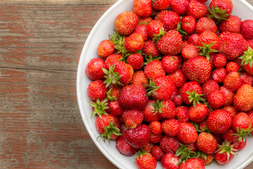 wild strawberries in a plate on a wooden table