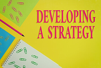 Poster - Text sign showing Developing A Strategy. Business photo showcasing Discussing the Ideas for New Goal Marketing Vision Planning Business Blank paper sheets message pencil clips binders plain colored