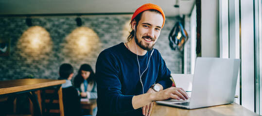 portrait of happy smiling hipster guy enjoying time for favourite music playlist during e learning i