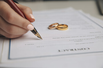 Woman signing marriage contract, closeup.