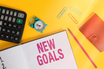 Wall Mural - Handwriting text New Goals. Conceptual photo a list of clearlydefined plans that an individual should attain Open notebook wallet calculator clips pencil alarm clock color background