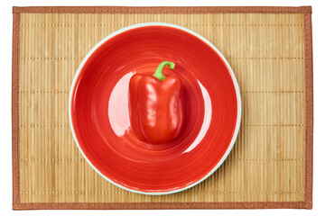 Wall Mural - red bell pepper on a red plate on a cane place mat