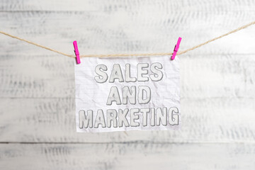 Fototapete - Handwriting text writing Sales And Marketing. Conceptual photo Business Advertising, Promotion, and Commercial Strategy Clothesline clothespin rectangle shaped paper reminder white wood desk