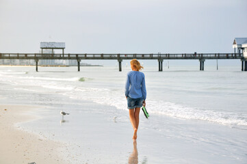 Barefoot woman walking on beach.