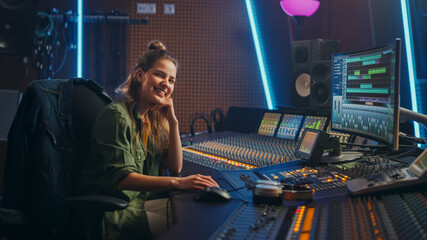Fototapete - Stylish, Beautiful Female Audio Engineer Working in Music Recording Studio, Uses Mixing Board Create Song. Looking at Camera Portrait of a Girl Artist Musician Working at Control Desk and Smiling