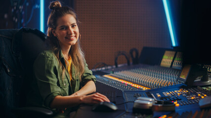 Poster - Stylish, Beautiful Female Audio Engineer Working in Music Recording Studio, Uses Mixing Board Create Song. Looking at Camera Portrait of a Girl Artist Musician Working at Control Desk and Smiling