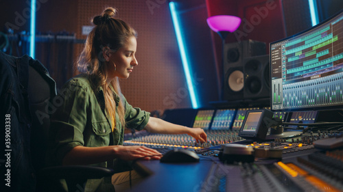 Fotografía Beautiful, Stylish Female Audio Engineer and Producer Working in Music Recording Studio, Uses Mixing Board and Software to Create Cool Song
