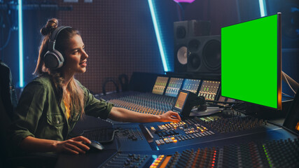 Fototapete - Stylish Female Audio Engineer / Producer Working in Music Record Studio, Uses Headphones, Green Screen Computer Display, Mixer Board, Control Desk to Create New Song. Creative Artist Musician.