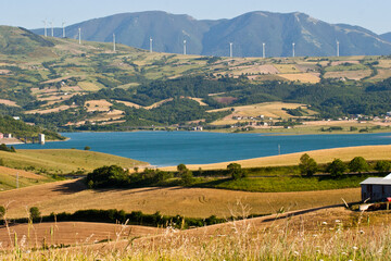 landscape with the lake of Conza della Campania and cultivated fields on the hills and wind turbines. Campania, Irpinia, Avellino, Italy.