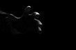 © Prapat - Close up scary hand of mysterious criminal in black glove reaching from the dark background in low key with black and white style