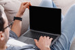 © Prostock-studio - Job searches at home. Guy with glasses works in laptop on couch