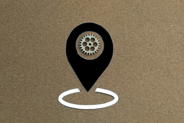 Fototapete - The geolocation sign is black. wooden gear on a light brown background. Location detection, technology.