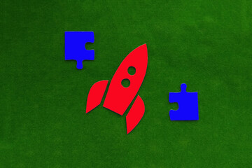 Red rocket flying up, two pieces of puzzles on a green background. Aiming for the top, work. Creative thinking.